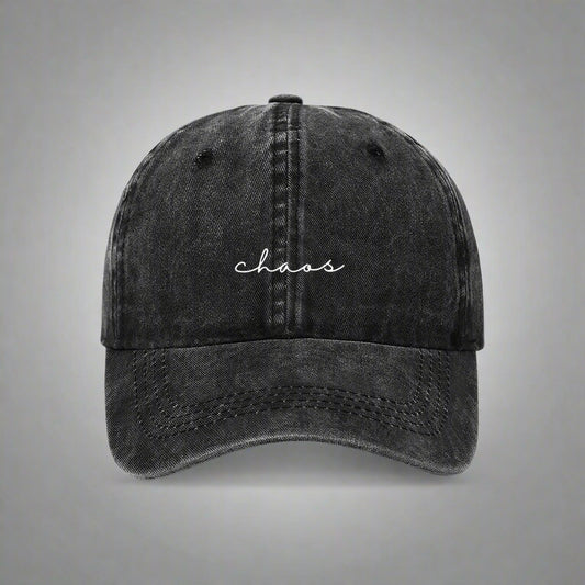 A black denim baseball cap with the word 'chaos' written in a cursive script on the front.