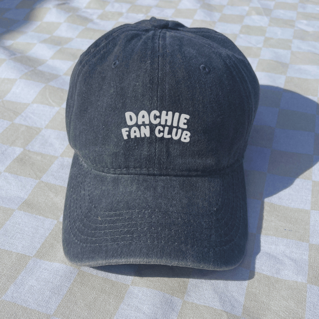 Black cap with 'Dachie Fan Club' text on a checkered floor