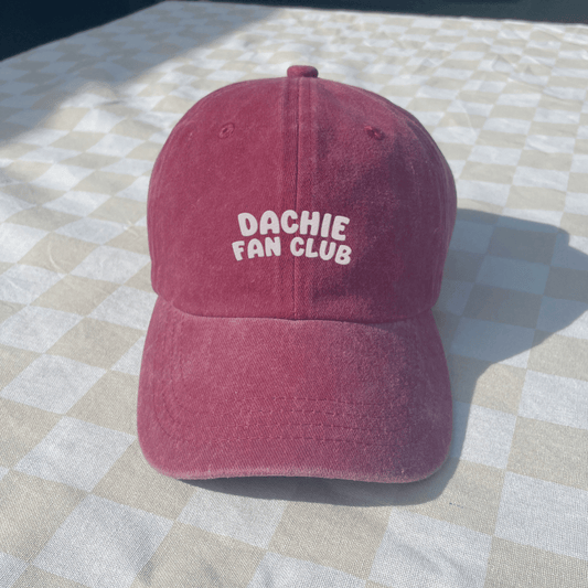 Red cap with 'Dachie Fan Club' text on a checkered tablecloth