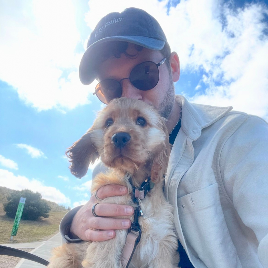 person holding a puppy wearing cap that says dog father