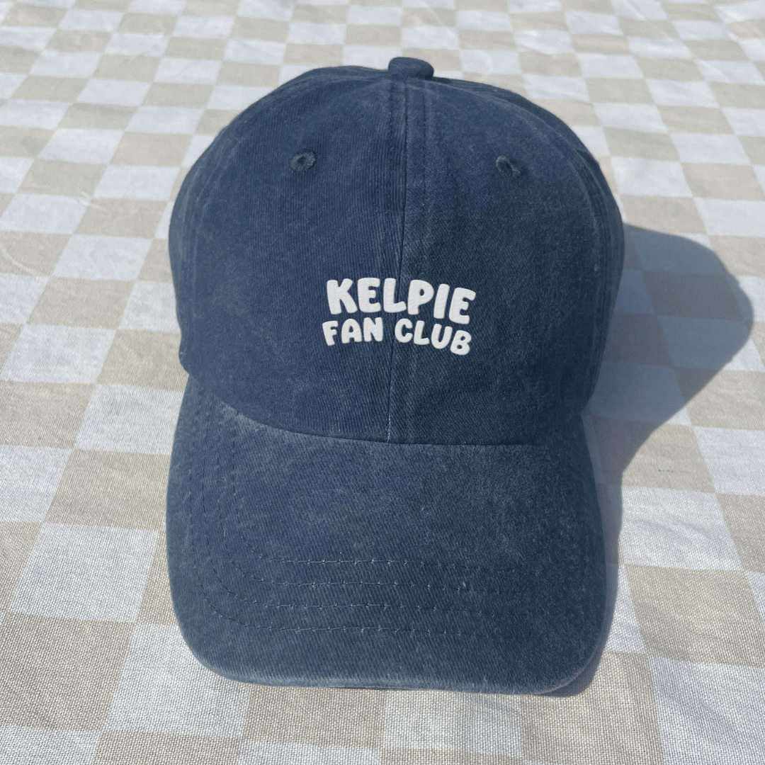 Blue cap with 'Kelpie Fan Club' text on a checkered floor