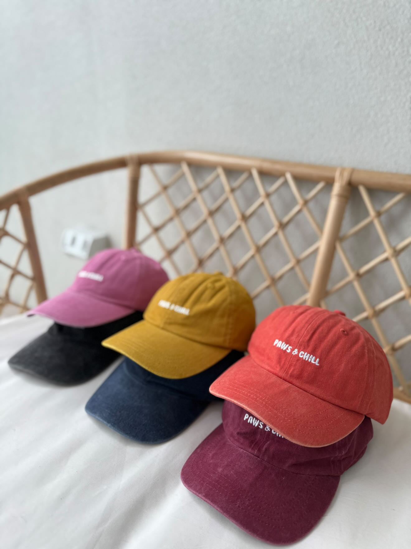 six different coloured embroidered caps that all say 'paws and chill.'