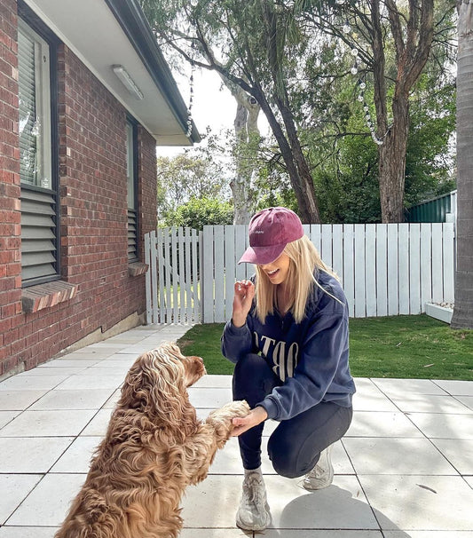 a girl kneeling with her cocker spaniel. her cap is maroon and says "spaniel mum"