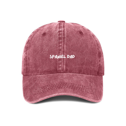 A red denim baseball cap with the text 'SPANIEL DAD' on it