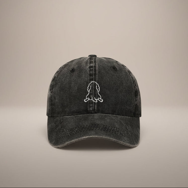 Black cap with a white outline of a dog splooting on a white background