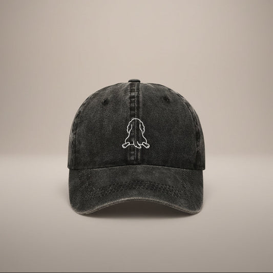 Black cap with a white outline of a dog splooting on a white background