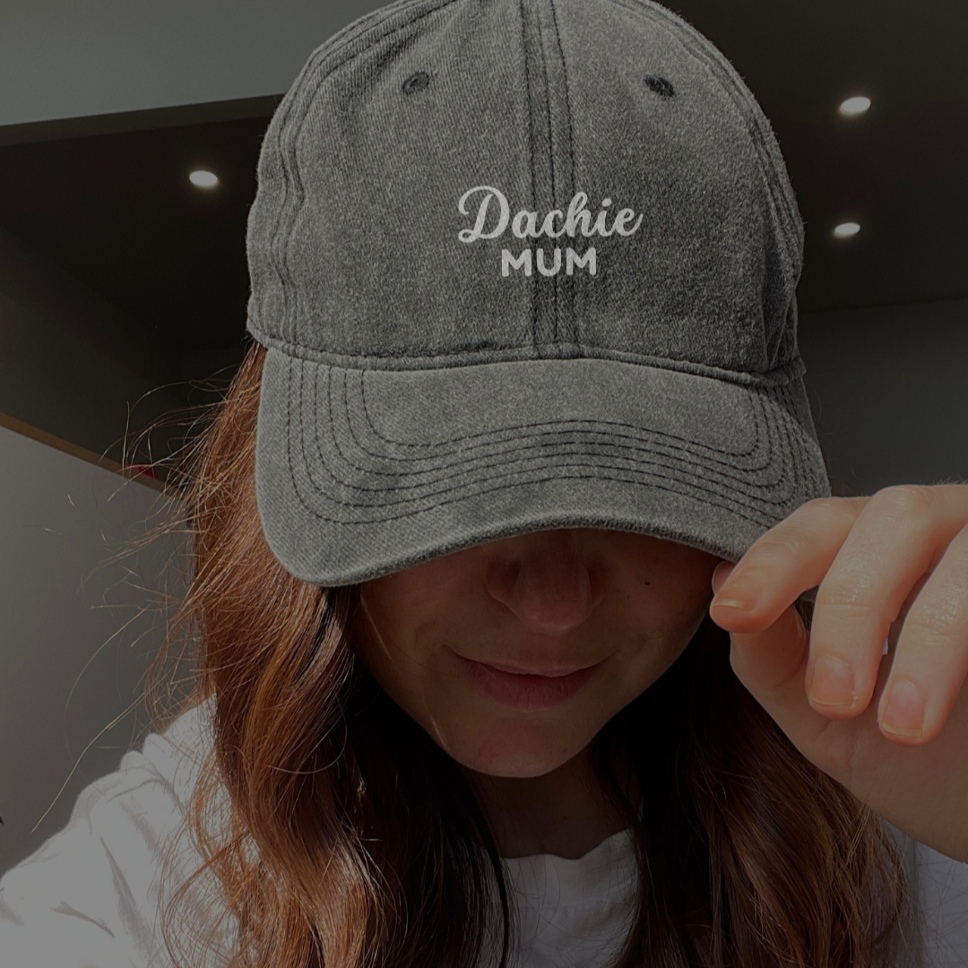 A person wearing a gray denim cap with the text 'Dachie Mum' embroidered on the front.
