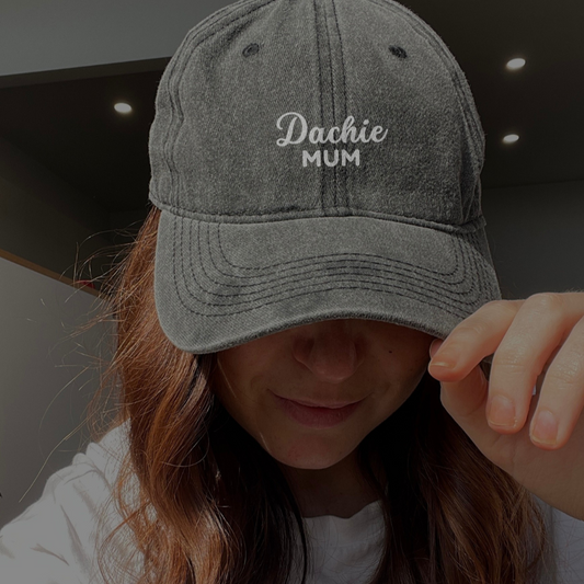 A person wearing a gray denim cap with the text 'Dachie Mum' embroidered on the front.