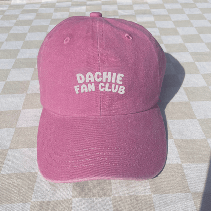 Pink cap with 'Dachie Fan Club' text on a checkered floor