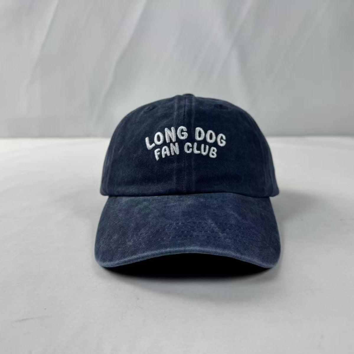 Navy blue cap with 'Long Dog Fan Club' text on a white background