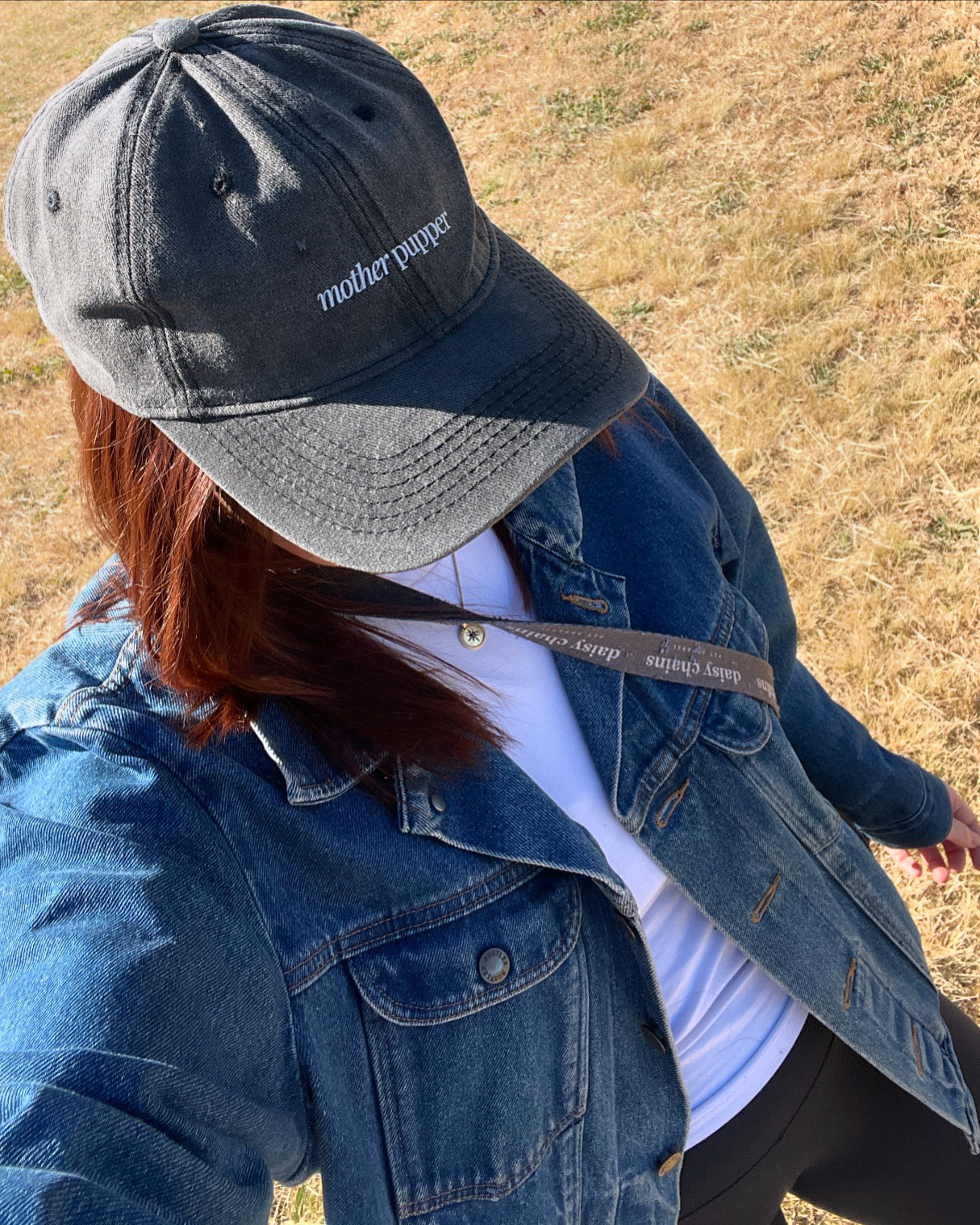 Girl wearing a denim jacket and cap with 'mother pupper' embroidered in white writing.