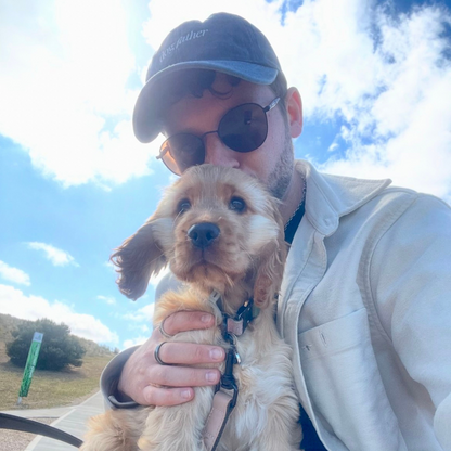 person holding a puppy wearing cap that says dog father