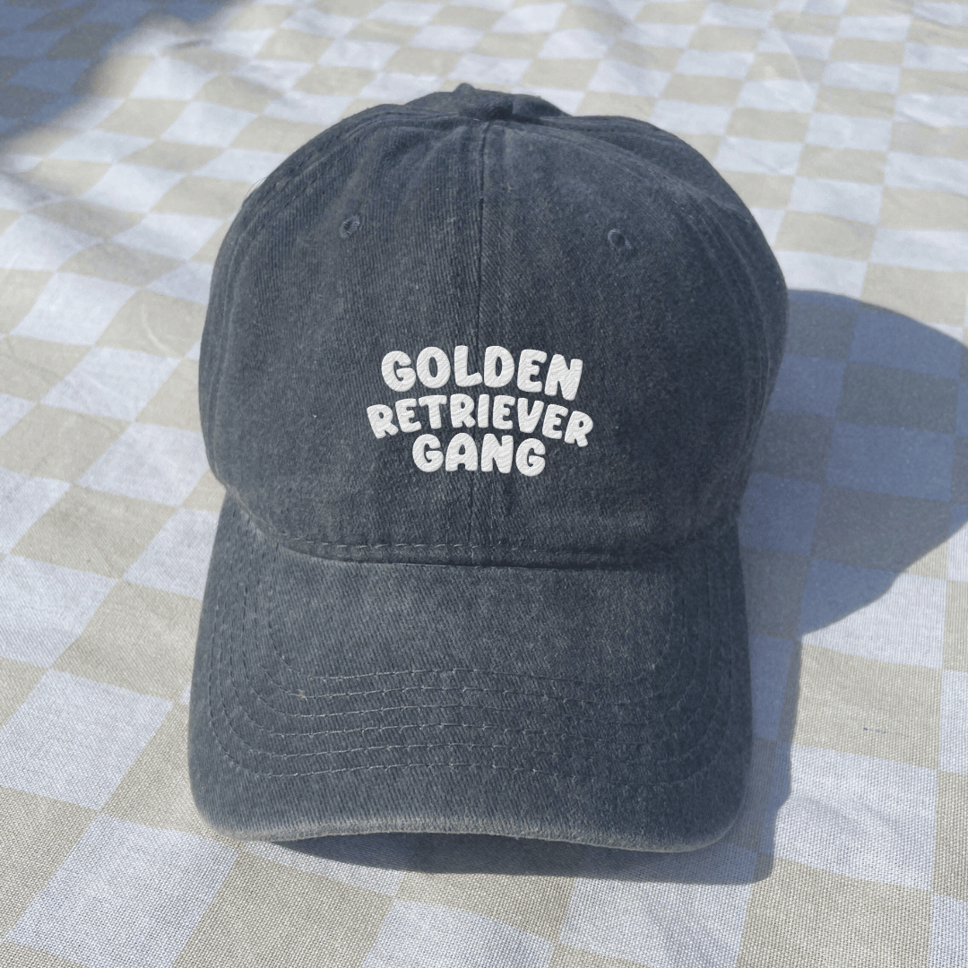 Black cap with 'Golden Retriever Gang' text on a checkered fabric background