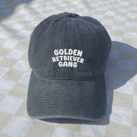 Black cap with 'Golden Retriever Gang' text on a checkered fabric background