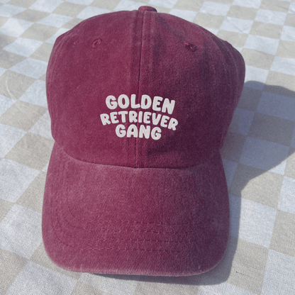 Maroon cap with 'Golden Retriever Gang' text on a checkered fabric background