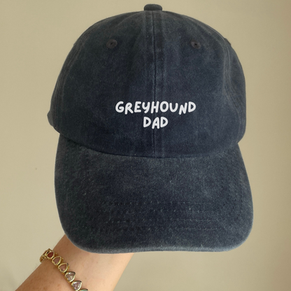 A navy blue baseball cap with 'GREYHOUND DAD' text embroidered on the front.