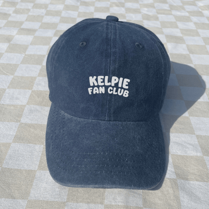 Blue cap with 'Kelpie Fan Club' text on a checkered floor
