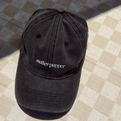 A black denim cotton cap with the text 'mother pupper' written in white on the front.