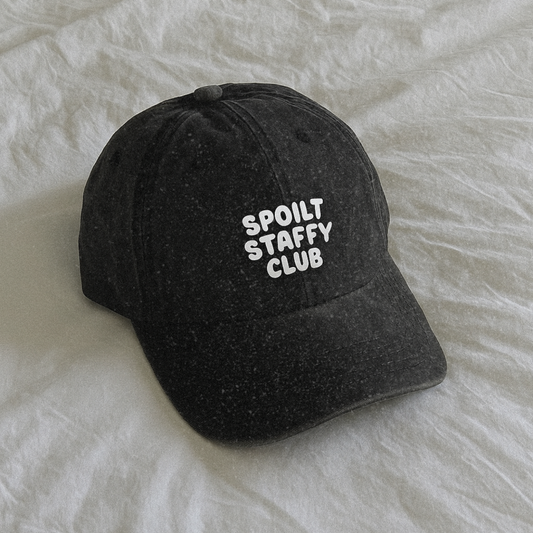 Black cap with 'SPOILT STAFFY CLUB' text on a white textured background