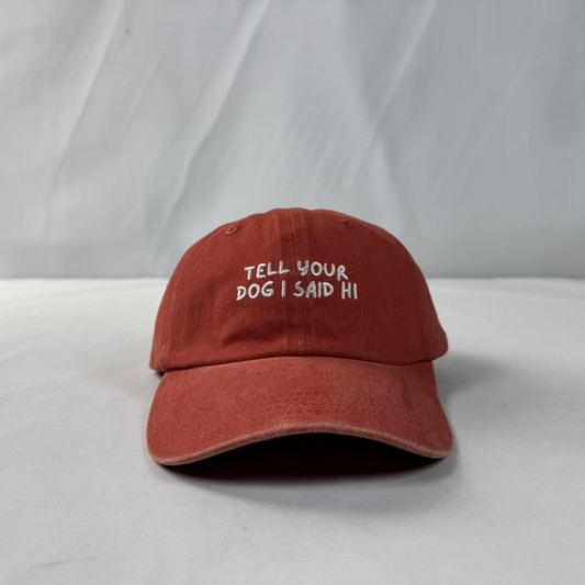 Orange cap with 'Tell your dog I said hi' text on a white background